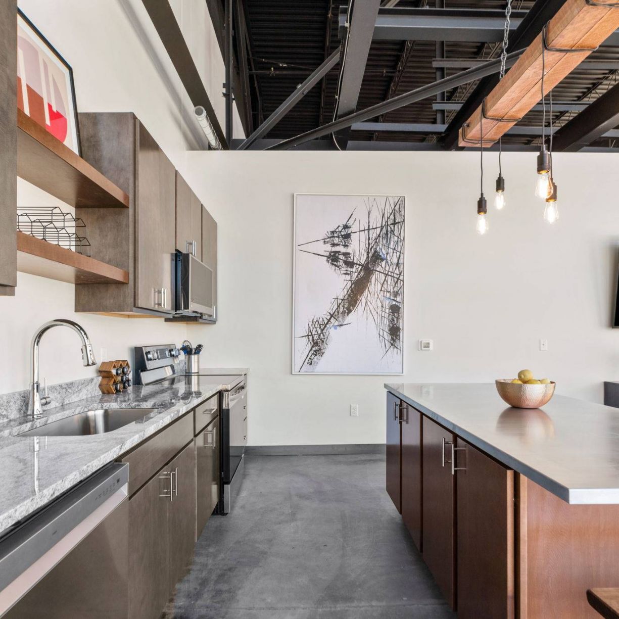 Close-up of the kitchen in Factory Lofts showcasing granite countertops, stainless steel appliances, and industrial-style lighting.